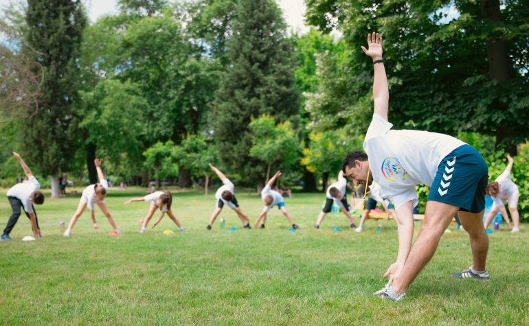 Schoolchildren stretching outdoors during a safely run sports clinic