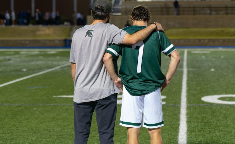 Coach encouraging a youth soccer player on the field for player safety