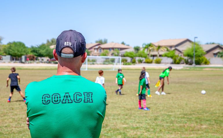 Coach guiding soccer players during a PTA supported sports activity
