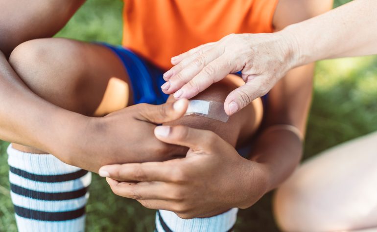Coach providing first aid after an injury at sports camp
